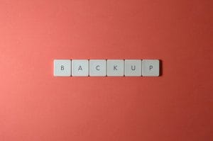Free Close-up of keyboard keys spelling 'BACKUP' placed on a coral-colored surface. Stock Photo